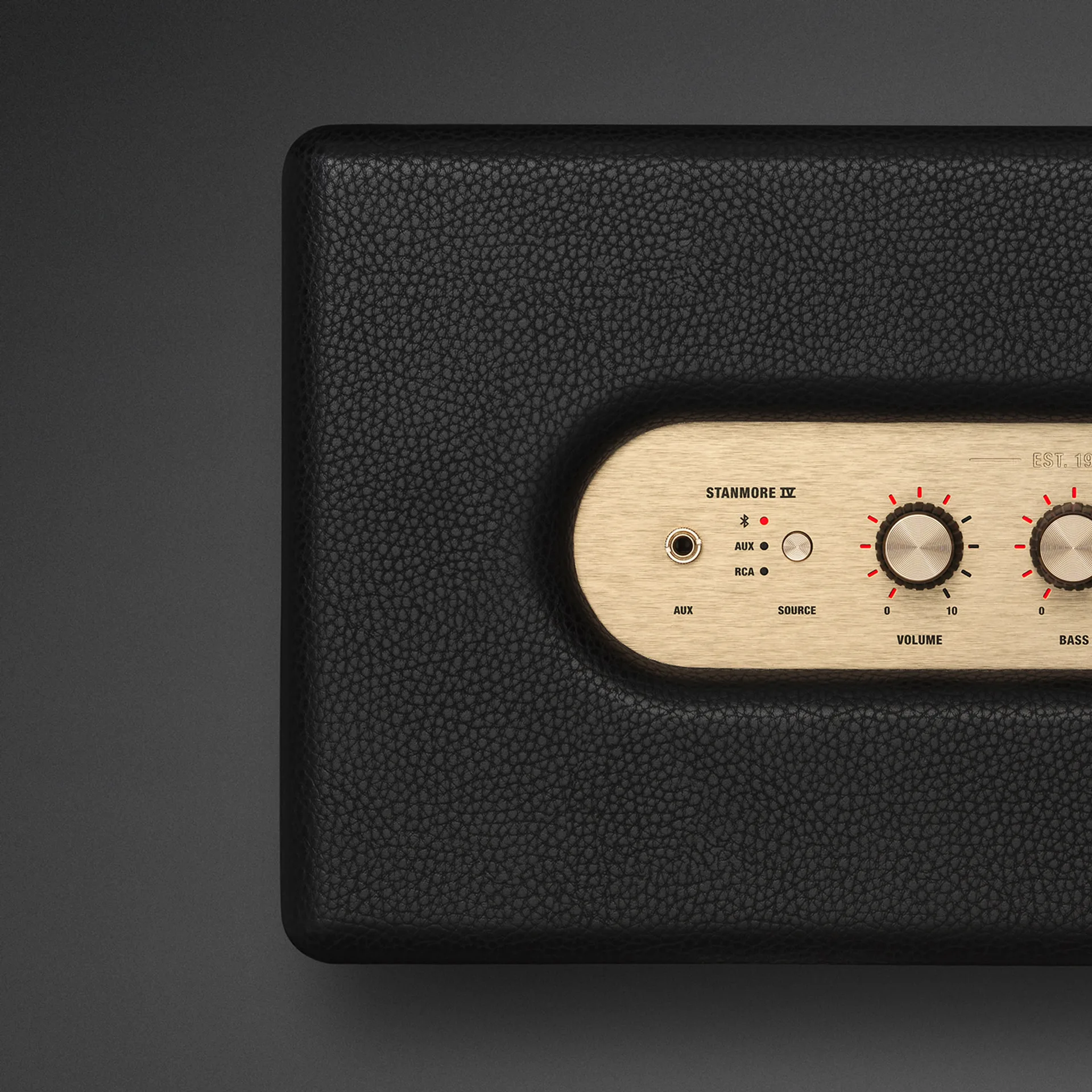 Close-up of Marshall Stanmore IV brass top panel showing AUX jack, Bluetooth AUX RCA source LEDs, and volume knob.